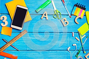 A pile of school supplies on a blue wooden table background. The concept of the educational process, doing homework.