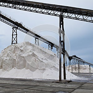 Pile of sea salt under conveyor of saline refinery photo
