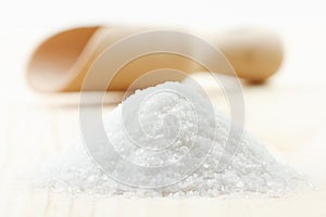 Pile of sea salt on wooden board, scoop