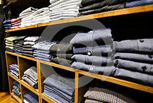 Pile of shirts lying on the shelf in the clothes shop. Shopping day and sale. Fashion elegant shopping