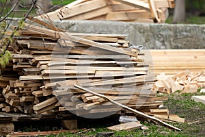 A pile of sloppily folded dry new wood-burning planks lying on the street in a vegetable garden at a cottage or a private house on