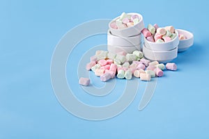 Pile of small colorfull marshmallow on blue background in bowl