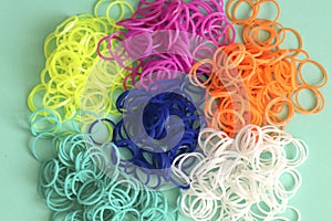 Pile of small round colorful rubber bands for making rainbow loom bracelets isolated on mint background