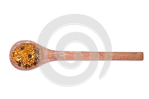 A pile of a spice mix for pilaf on wooden spoon isolated on white background.