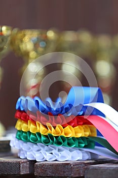 Pile of sport trophies and badges rosettes for the winners on show jumping competition