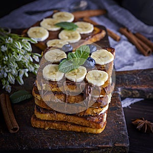 A pile of square fried bread slices with chocolate and banana