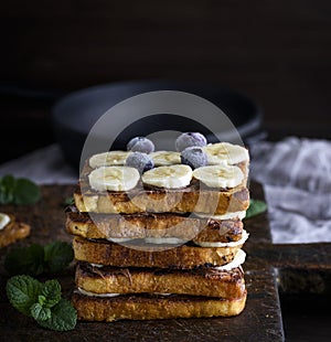 pile of square fried bread slices with chocolate and banana slices