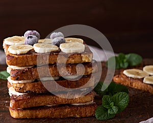 Pile of square fried bread slices with chocolate and banana slices