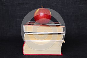 Pile stack of books with red apple on top, back to school concept, education concept, copy text space, black background