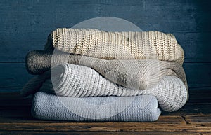 Pile stack folded of knitted warm clothes on wooden background, sweaters, knitwear