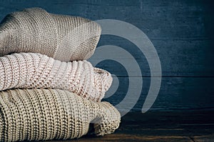 Pile stack folded of knitted warm clothes on wooden background, sweaters, knitwear