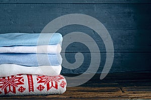 Pile stack folded of knitted winter clothes on wooden background, sweaters, knitwear
