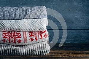 Pile stack folded of knitted winter clothes on wooden background, sweaters, knitwear