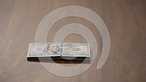 Pile stack of hundred dollar bills on walnut table   shot