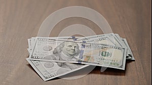 Pile stack of hundred dollar bills on walnut table   shot