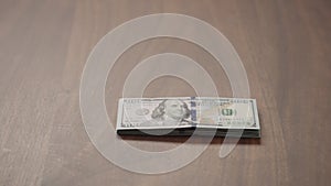 Pile stack of hundred dollar bills on walnut table slide shot