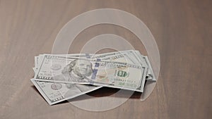 Pile stack of hundred dollar bills on walnut table slide shot