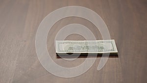 Pile stack of hundred dollar bills on walnut table slide shot