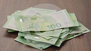 Pile stack of hundred euro bills on walnut table slide shot