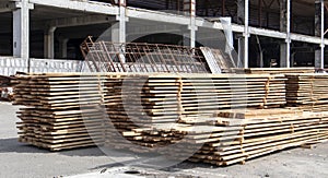 Pile of stacked wooden planks at a construction site. Wooden boards, lumber. Industrial edged timber. Wooden rafters for