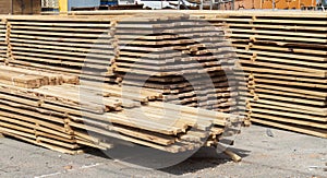 Pile of stacked wooden planks at a construction site. Wooden boards, lumber. Industrial edged timber. Wooden rafters for