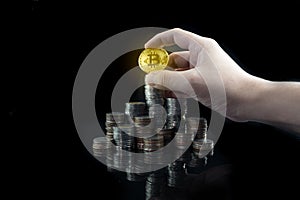 Pile of stacking coins with shiny golden bitcoin on top with grabbing hand, king of all coins, most valuable coin, rising