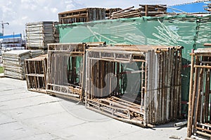 A pile of steel scaffolding with brown rust on the cocrete floor in front the building
