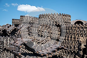 A pile of steel tracks combat Soviet tanks against the blue sky.