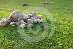 Pile of stones, granite, lies on the grass on a summer day