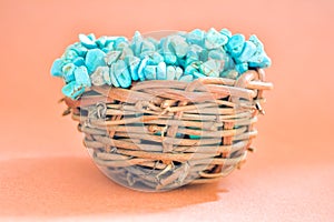 Pile stones of raw Turquoise in small wooden nest on a brown background