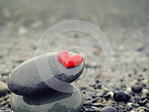 A pile of stones on the seashore, red heart at the top, zen relax