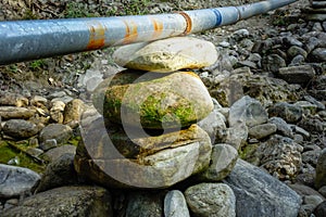 A pile of stones supporting water pipe line in village. A water pipe line in country side in India