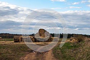 A pile of straw bales lying close to the sandy road