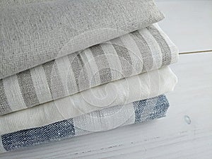 Pile of striped white grey blue linen cotton fabrics on white background.