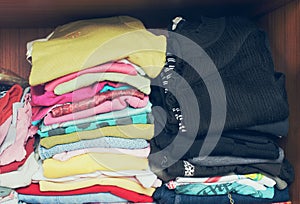 Pile of T-shirt clothes in closet. Stack of many color folded woman shirts overlay