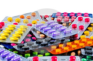 Pile of tablet pills on white background. Yellow, purple, black, orange, pink , green tablet pills in blister pack.