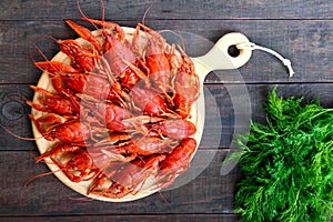 A pile of tasty boiled crawfish on a round wooden tray on a dark table.