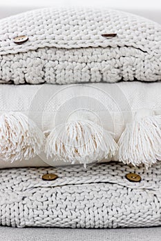 A pile of textured knitted pillows with buttons and tassels