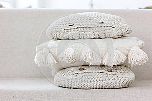 A pile of textured knitted pillows with buttons and tassels