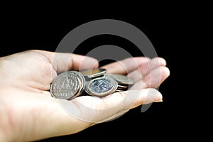 Pile of Thai coins on left Asian woman hand on black background, saving money concept