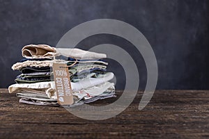 Pile of things lie on a wooden table. Cotton, linen items in pastel colors shirts, shreds of fabric