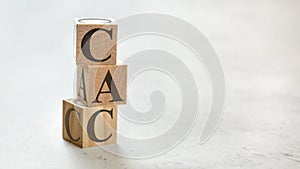 Pile with three wooden cubes - letters CAC meaning Customer Acquisition Cost on them, space for more text / images at right side