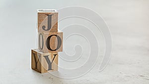 Pile with three wooden cubes - letters JOY on them, space for more text / images on right side