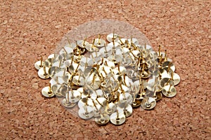 A pile of thumbtacks on a cork board.