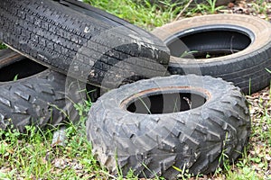 Pile of tires sitting in the grass and weeds