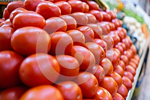 Pile of tomatoes on stand with more vegetables as background