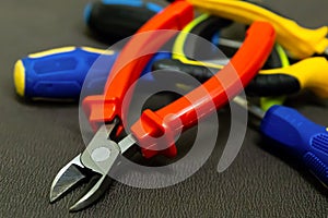 Pile of tools of hand red nippers on the background of plastic pens screwdriver macro background construction