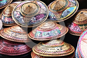 Pile of traditional Thai hats which are painted with rural scenes, and made of bamboo, Phuket, Thailand