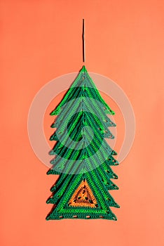 A pile of triangle crochet motifs arranged in the shape of a conifer tree with crochet hook placed vertically above it.