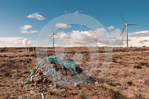 Pile of turf fossil fuel drying on a sun, wind turbine in the background. Old source of energy and new technology concept. Warm